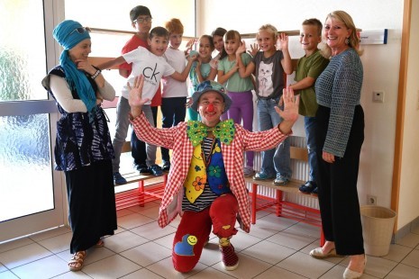 Stadträtin Sonja Schwentner (li.) und Volksschuldirektorin Ulrike Bauer (re.) mit dem Fair-Clown Hugo und den fröhlichen Kindern.