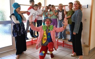 Stadträtin Sonja Schwentner (li.) und Volksschuldirektorin Ulrike Bauer (re.) mit dem Fair-Clown Hugo und den fröhlichen Kindern.